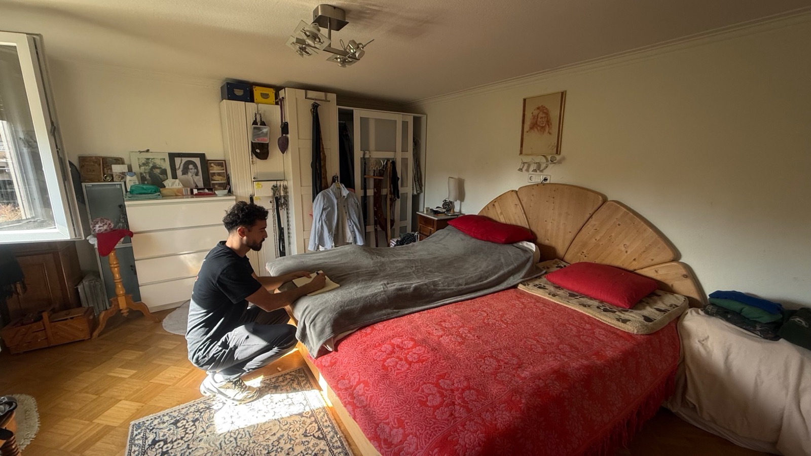 Mitarbeiter baut in einem eingerichteten Schlafzimmer ein Doppelbett ab