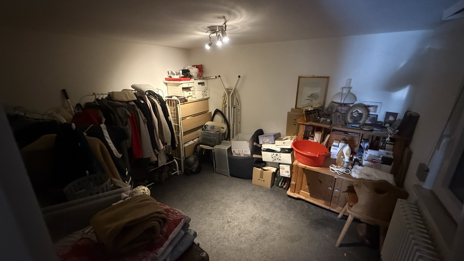 Kleiderzimmer mit Kleiderstangen, Kommode und Schreibtisch vor der Auflösung