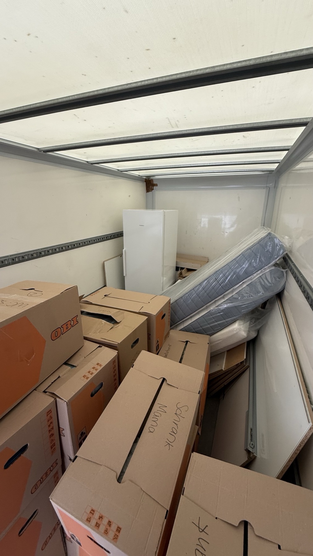 Voll beladener Laderaum mit beschrifteten Kartons, foliierten Matratzen und einem zerlegten Schrank