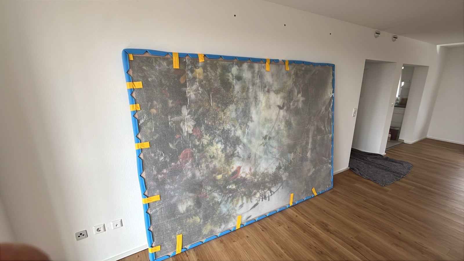 Großformatiges Bild mit Kantenschutz und Folie gesichert, in einer geräumten Wohnung