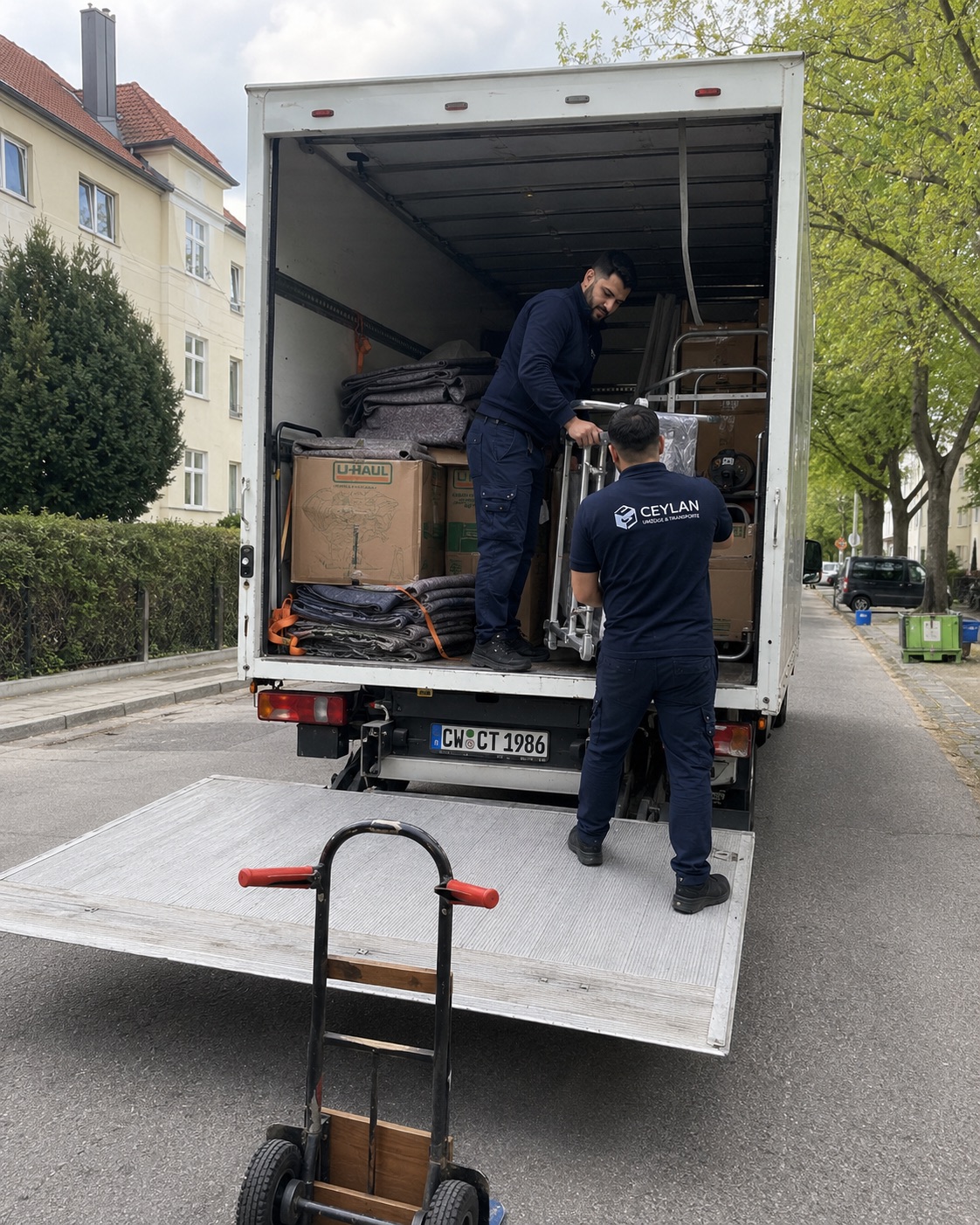 Zwei Mitarbeiter beladen den Transporter mit Kartons und Möbeln