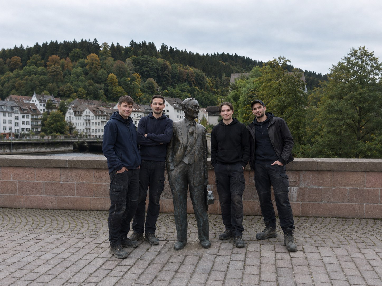 Das Team von Ceylan Umzüge & Transporte auf der Brücke in Calw, im Hintergrund Fachwerkhäuser und bewaldeter Hang
